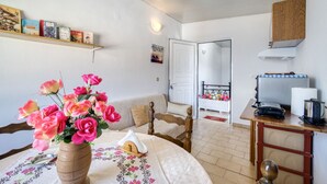 Un salon chaleureux avec une table ronde, un canapé, une bibliothèque et un coin cuisine équipé d’un grille-pain.