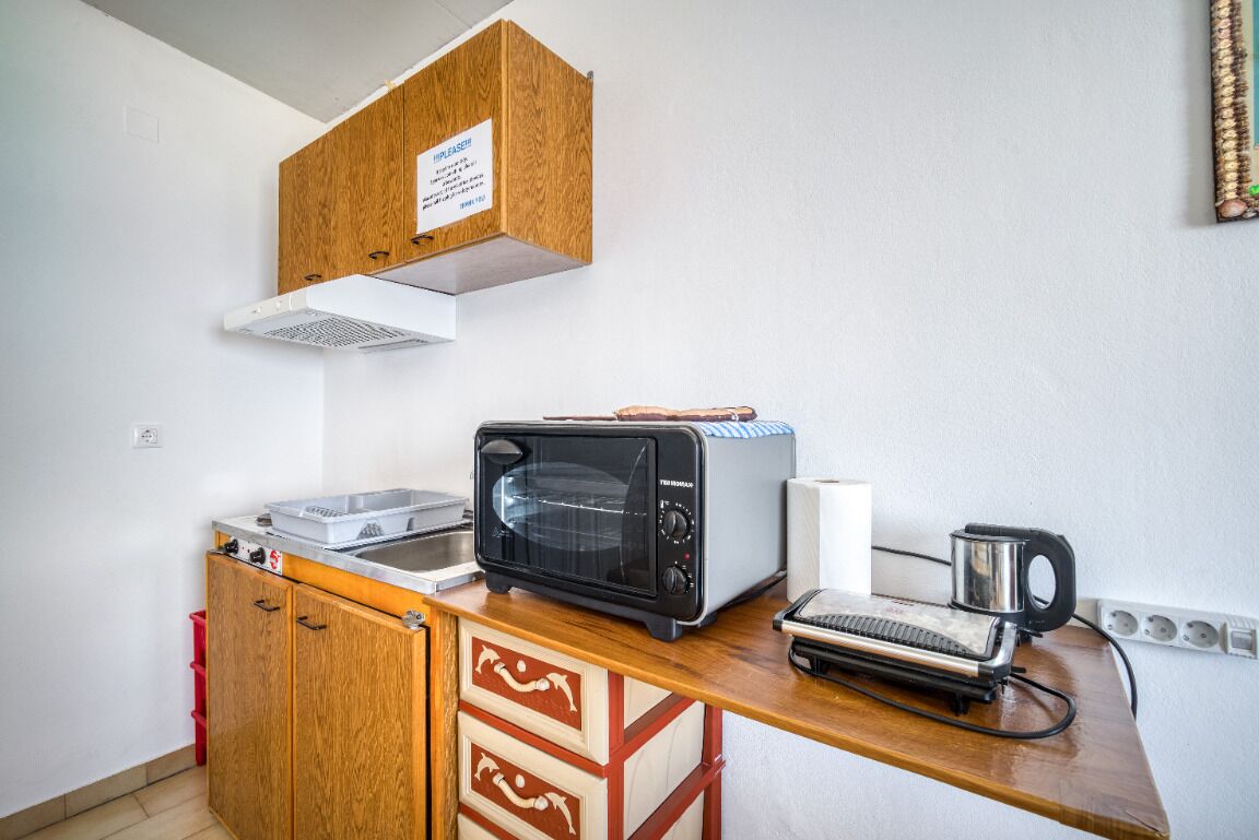 A compact kitchenette with a toaster, a small oven, and a coffee maker on a wooden countertop.