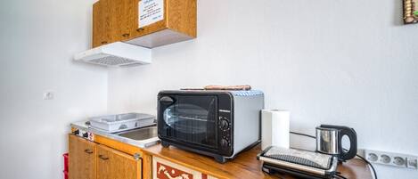 A compact kitchenette with a toaster, a small oven, and a coffee maker on a wooden countertop.