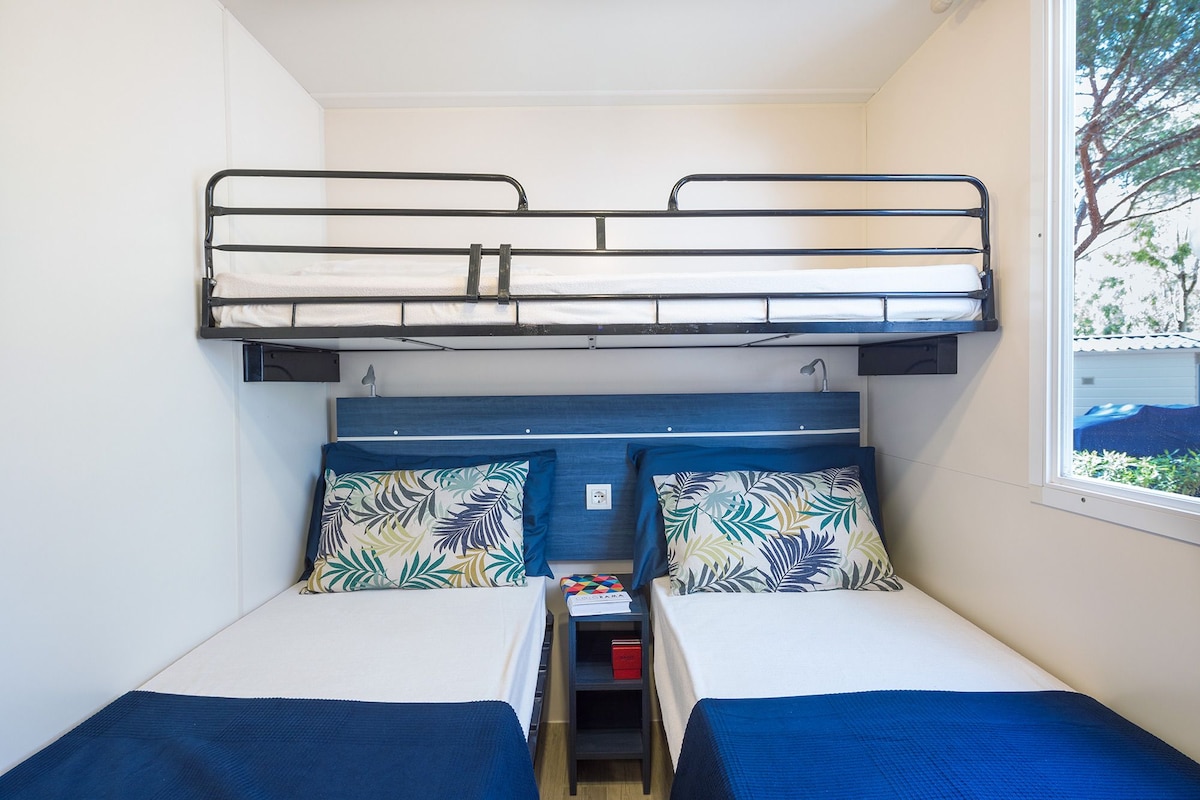 Une chambre avec un lit superposé, une fenêtre, un bureau et une table de chevet.