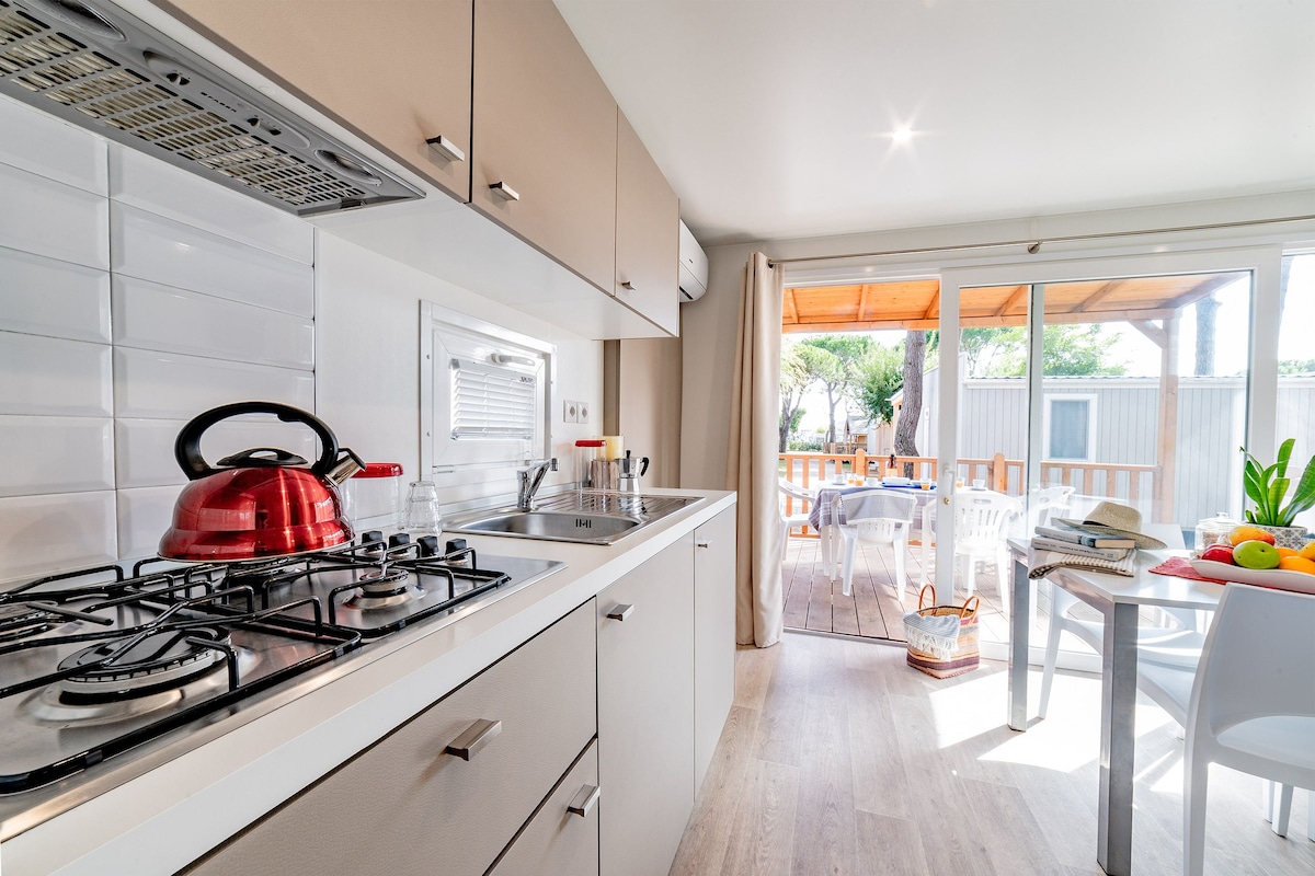 Une cuisine moderne équipée d’une cuisinière à gaz, d’une bouilloire et de meubles blancs.