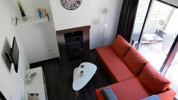 Een moderne woonkamer met een bank, een flatscreen televisie, een open haard en een groot raam.