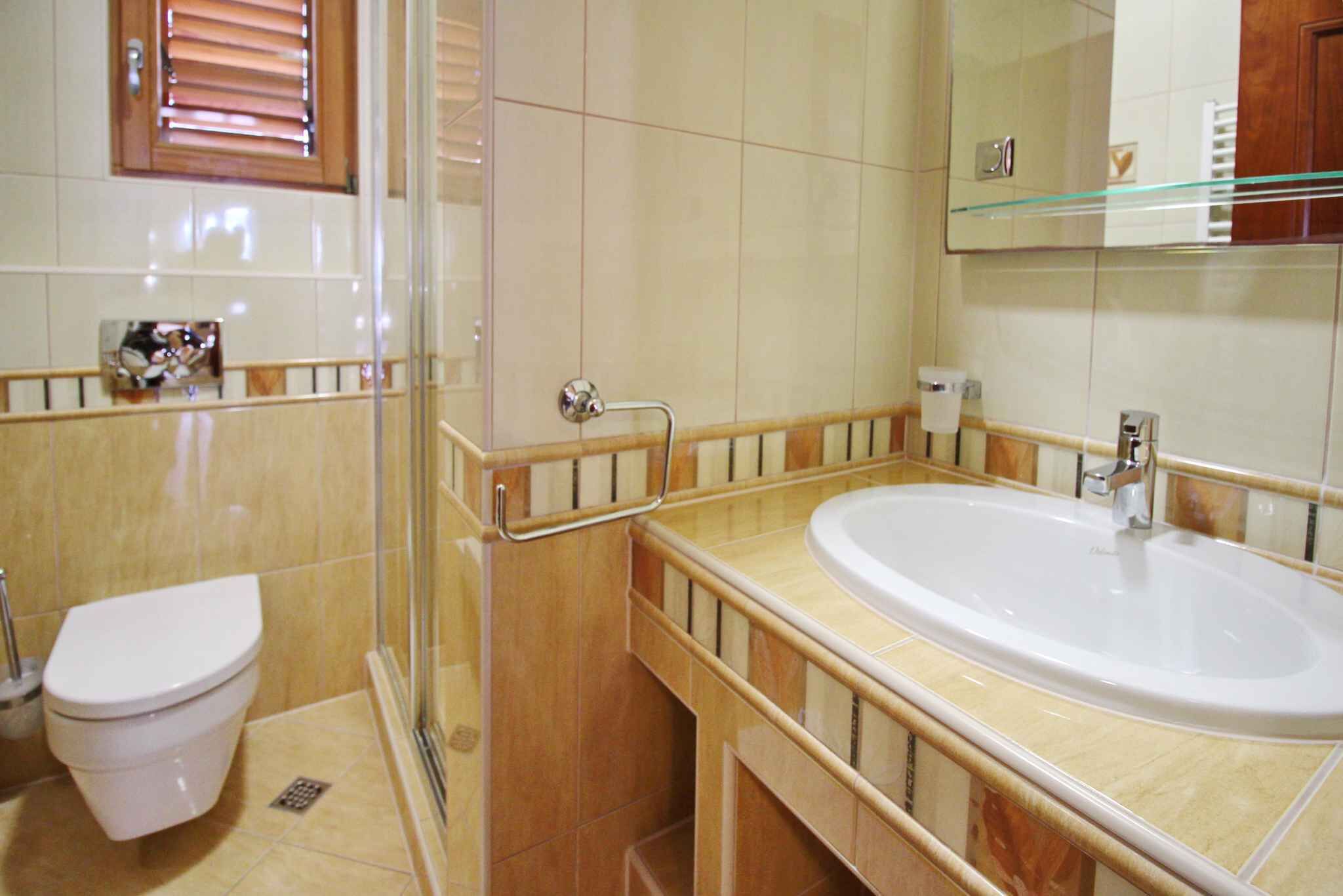 Un bany amb vàter, plat de dutxa amb envàs de vidre i un lavabo amb mirall a la part superior.