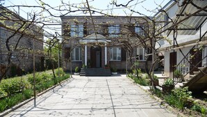 A courtyard with a stone pathway leading to a building with a front entrance and steps. - Olimpo Guest House (Akhaltsikhe)