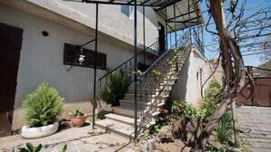 A staircase leading to a balcony with a metal railing, surrounded by potted plants and a tree. - Olimpo Guest House (Akhaltsikhe)