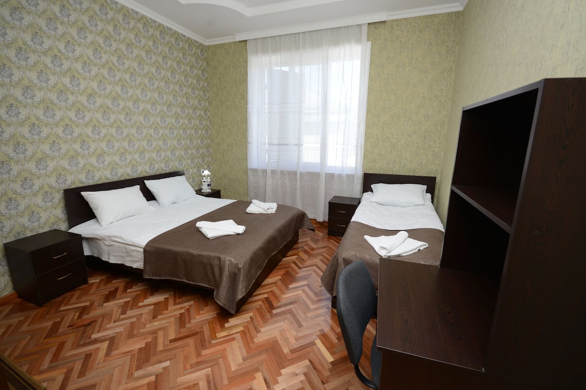 A hotel room with two beds, a desk, and a TV.
