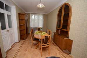 A dining area with a wooden table and chairs, a cabinet, and a door. - Olimpo Guest House (Akhaltsikhe)