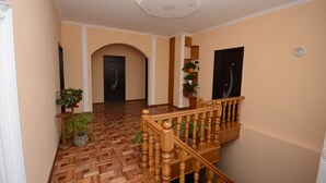 A hallway with wooden flooring, a staircase with wooden balusters, and a ceiling with recessed lighting. - Olimpo Guest House (Akhaltsikhe)