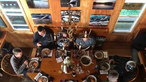 Une table de salle à manger ronde en bois, sur laquelle sont disposées de nombreuses assiettes remplies de nourriture, et entourée de chaises.