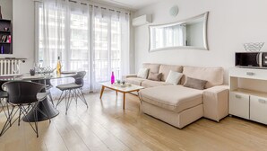 Ein modernes Wohnzimmer mit einem beigefarbenen Sofa, einem Glastisch und einem Essbereich mit einem Glastisch und Stühlen.