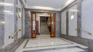 Ein Flur mit Marmorboden und einer Holztür, die zu einer Treppe führt.