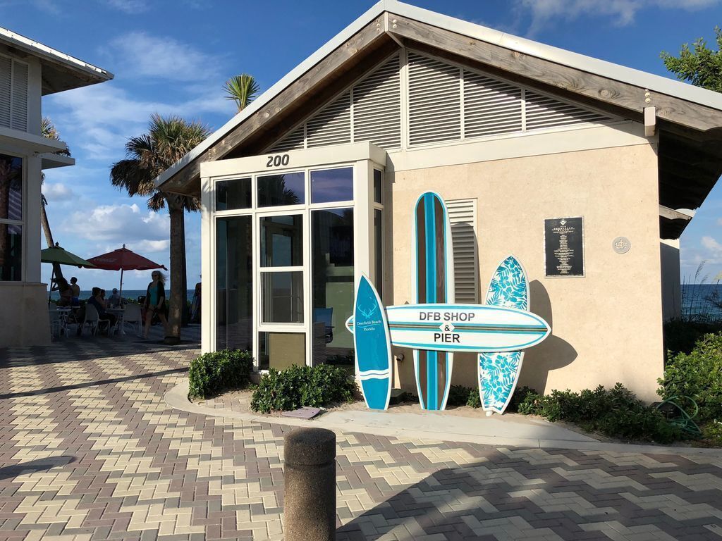 Un edificio con un letrero que dice 'DFB SHOP & PIER' y tablas de surf exhibidas en el exterior.