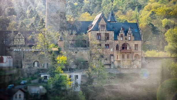 Un edificio histórico con una torre destacada, rodeado de abundante vegetación y otras construcciones tradicionales.