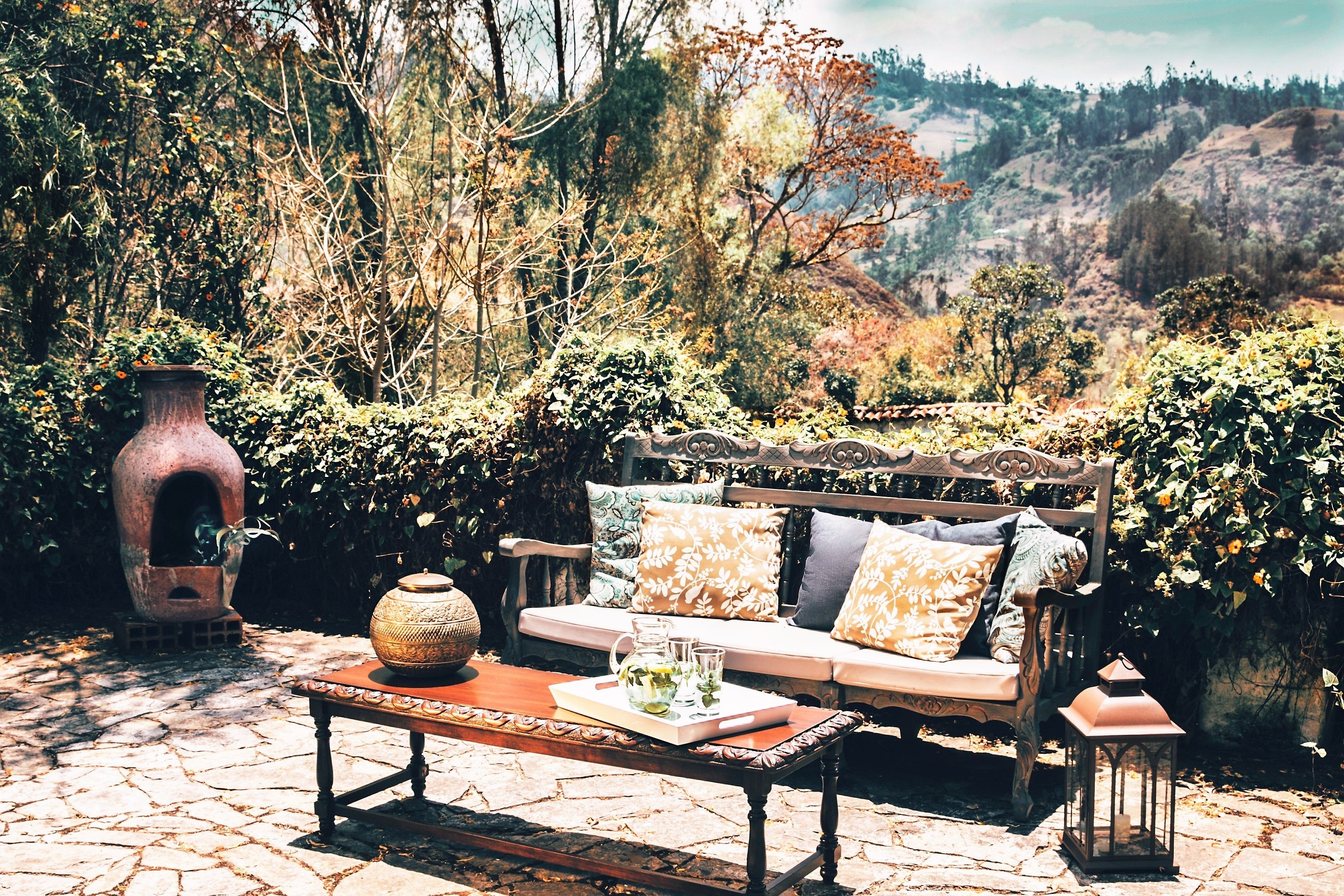 An outdoor seating area with a stone table, a bench, and a lantern.