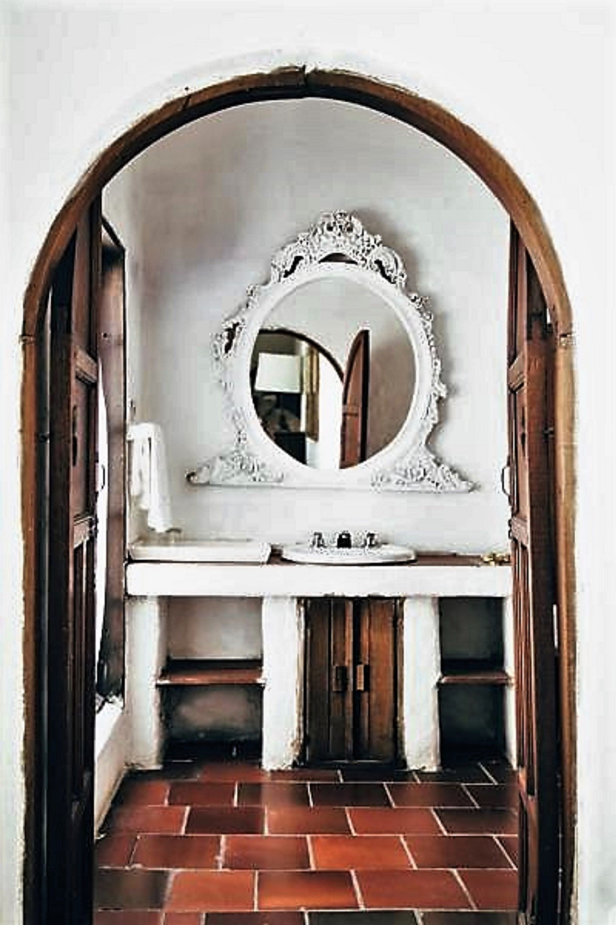 A bathroom with a white vanity, a mirror with an ornate frame, and a tiled floor.