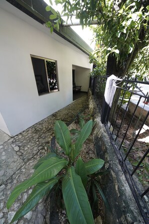 A pathway leading to a white building with a window and a small door. - Hotel Sevilla Palenque (Palenque)