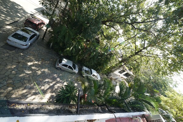 Un área de estacionamiento con varios automóviles y frondosos árboles verdes.