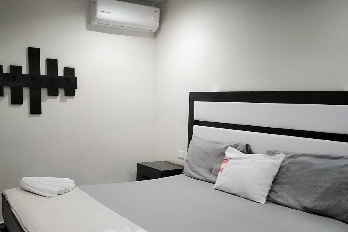 Un dormitorio moderno con una cama grande, ropa de cama blanca y cabecera blanco y negro.