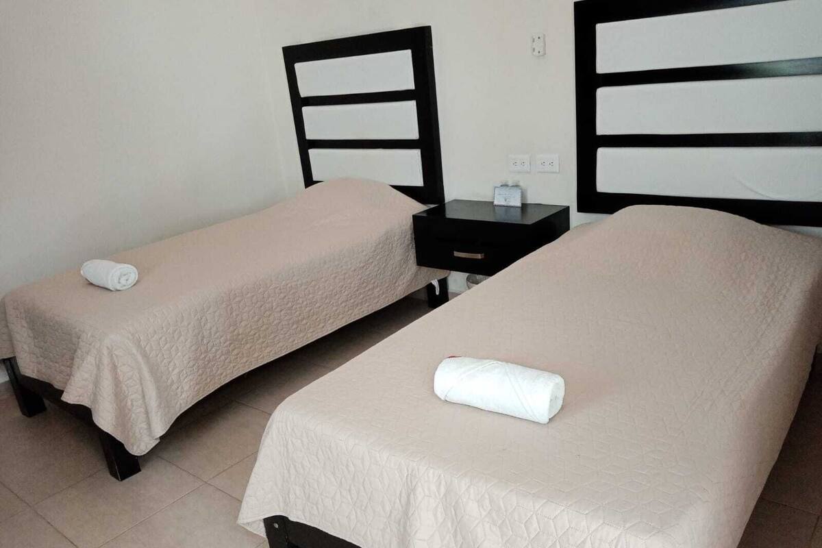 Dos camas individuales con cabeceros, mesitas de noche y un enchufe en la pared.