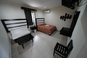 A bedroom with two beds, a desk, a chair, a small table, and a window with curtains. - Hotel Sevilla Palenque (Palenque)
