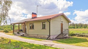 Einbungalow mit einer Laube, einem Schornstein und einem kleinen Vorgarten mit Kiesweg.