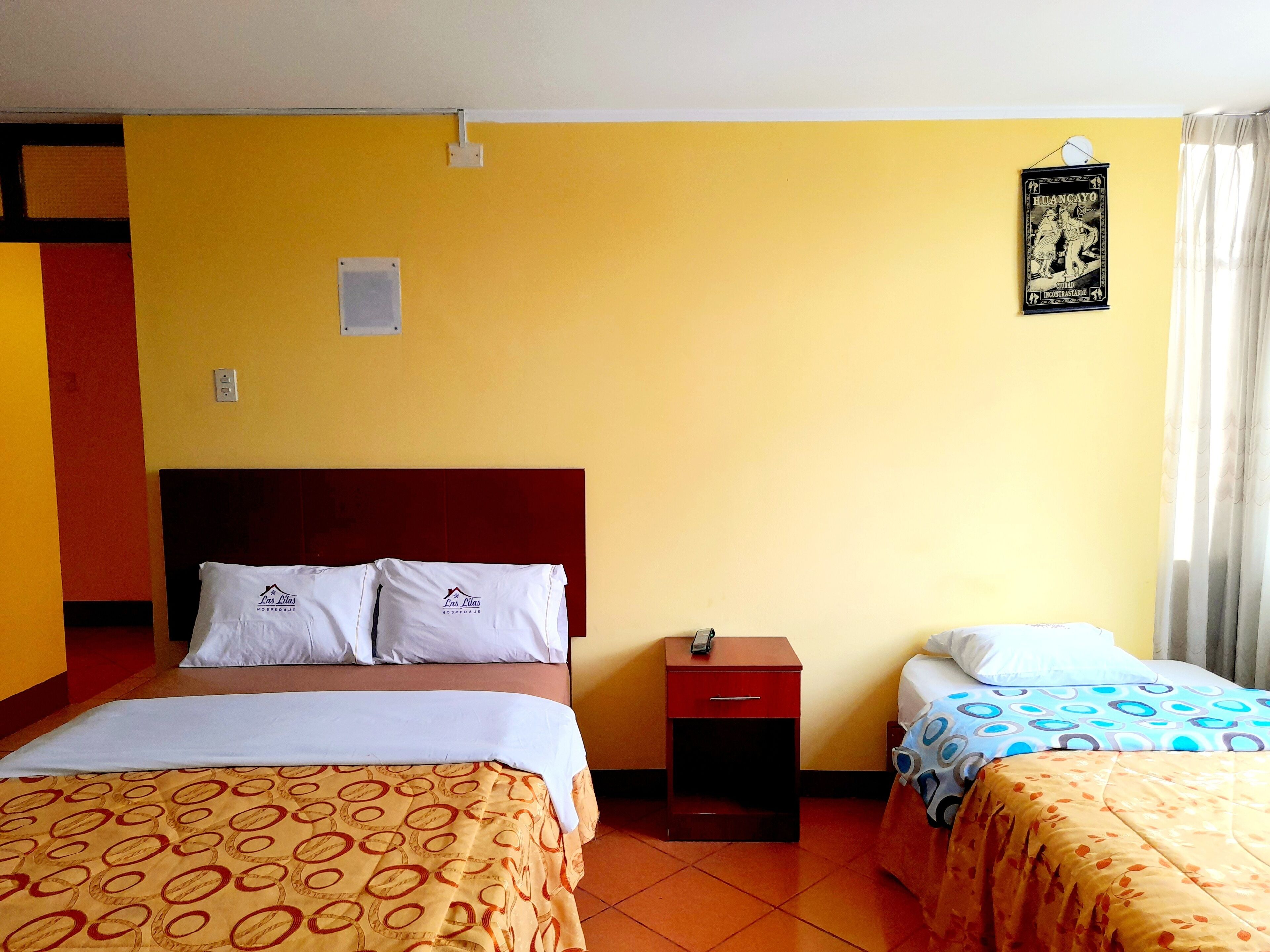 A hotel room with two beds, a nightstand, and a poster on the wall.
