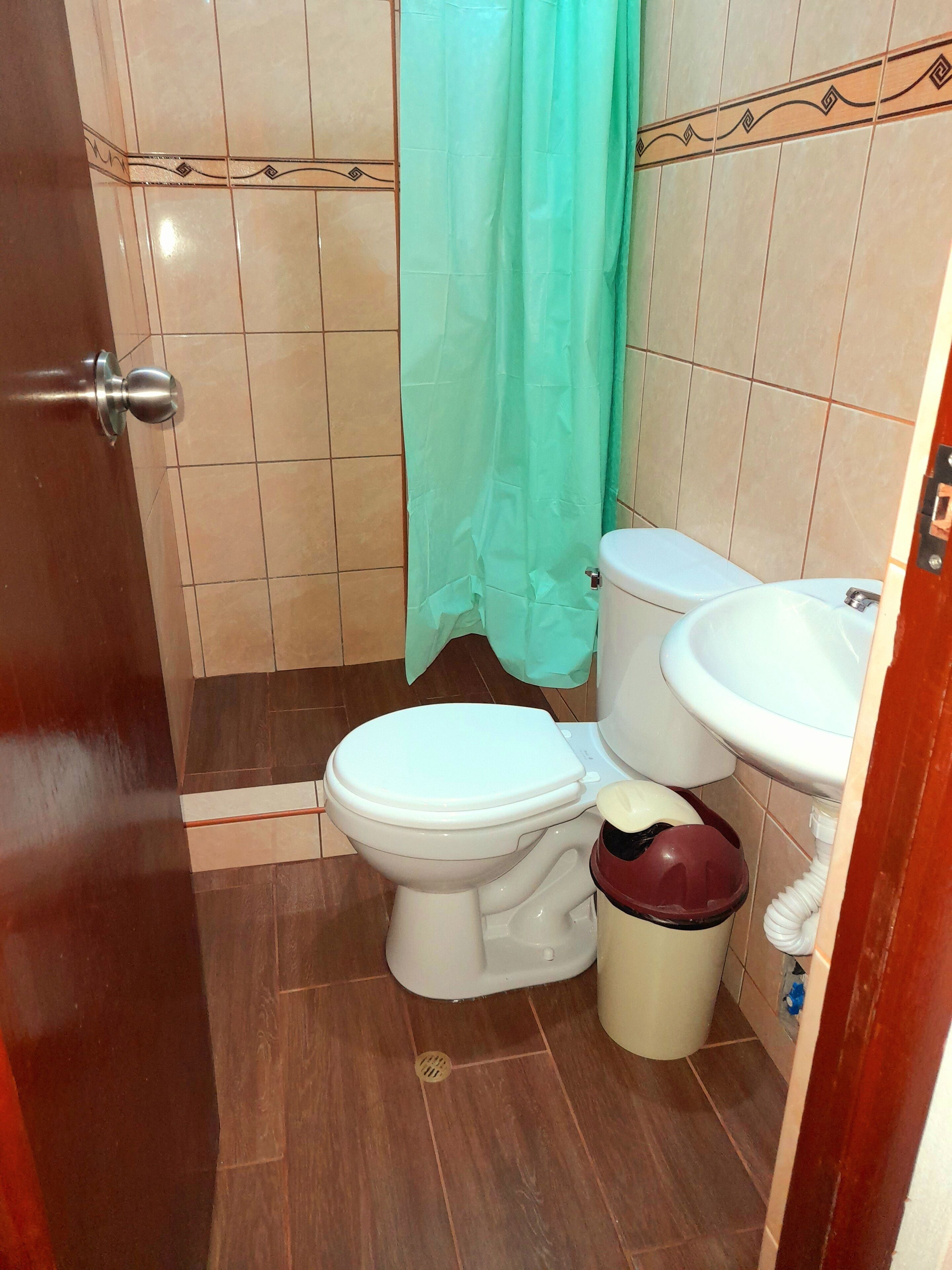 A bathroom with a toilet, sink, and a trash bin.