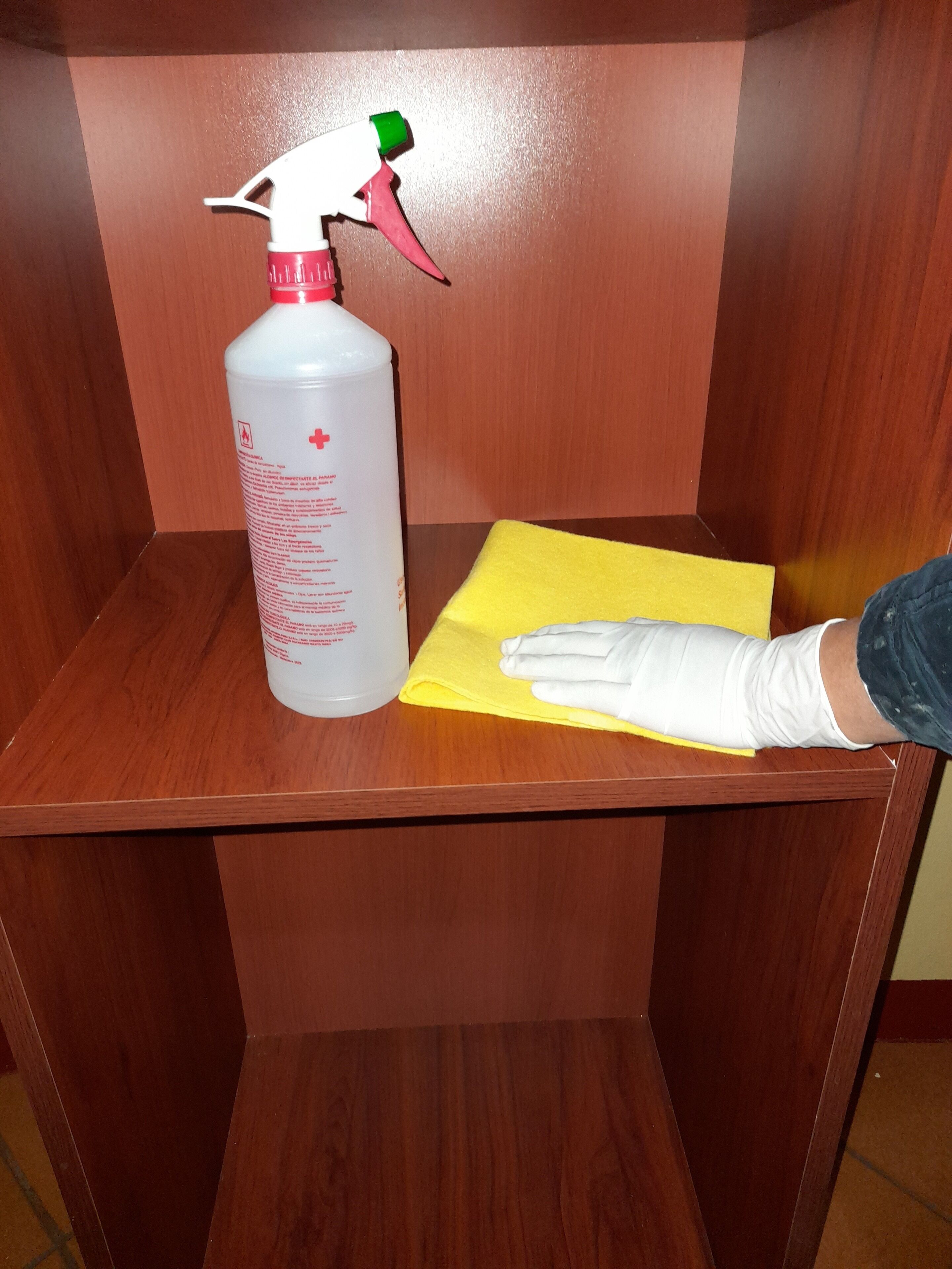 A spray bottle and a yellow cloth on a wooden surface.
