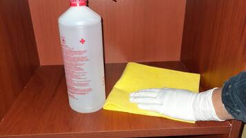 A spray bottle and a yellow cloth on a wooden surface.