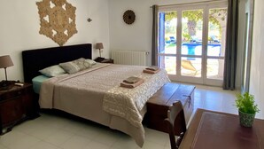 A bedroom with a bed, bedside tables, a lamp, a decorative wall piece, and a view of a pool through a glass door. - VILLA LOS ARCOS COSTA BRAVA
Breathtaking sea views & relaxation amidst nature (Lloret de Mar)