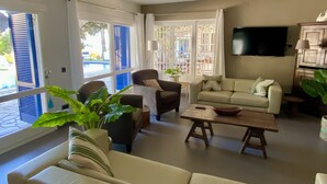 A living room with a sofa, armchairs, a coffee table, and a TV. There are windows with blue shutters and a balcony visible. - VILLA LOS ARCOS COSTA BRAVA
Breathtaking sea views & relaxation amidst nature (Lloret de Mar)
