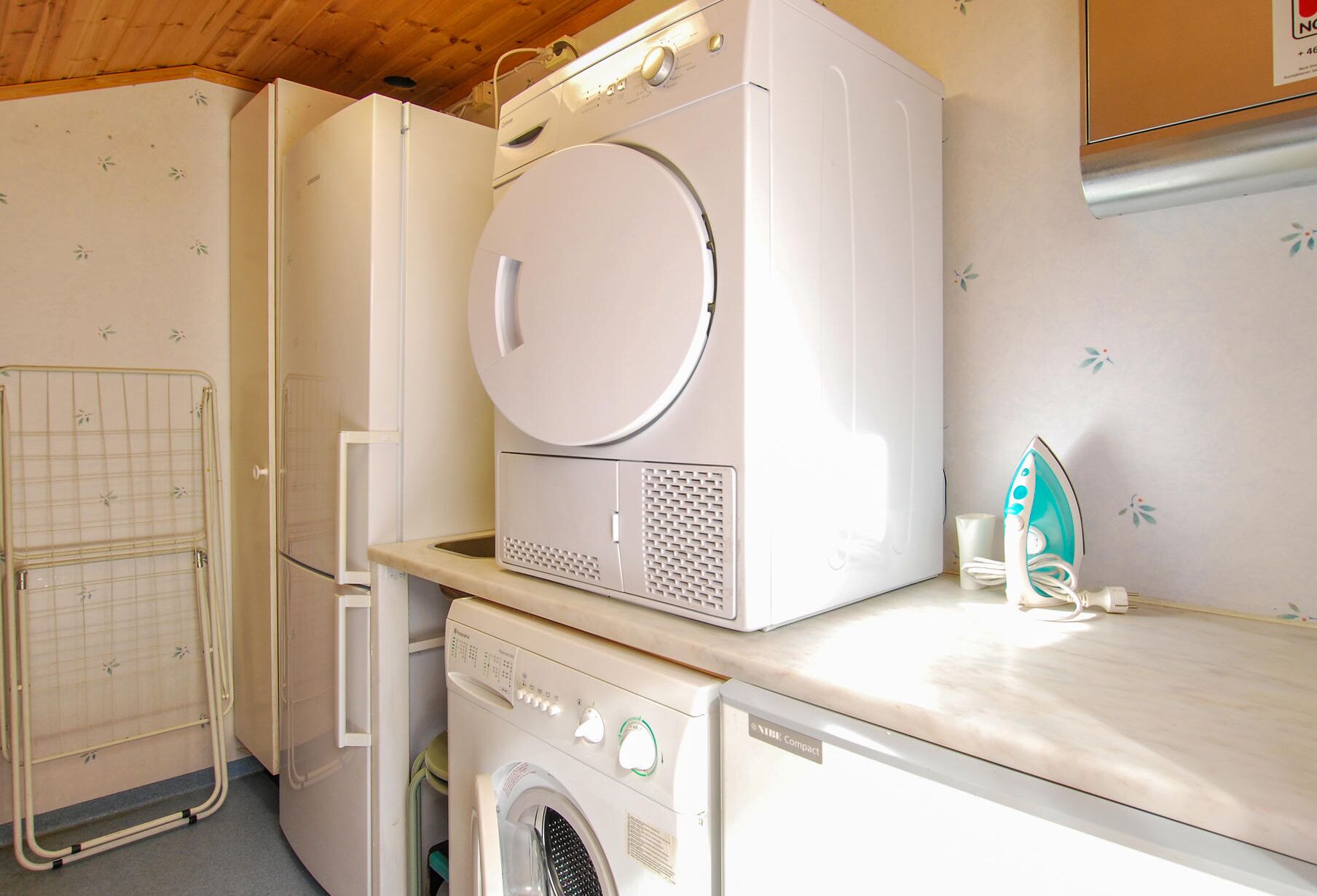 A compact laundry room with a washing machine, dryer, and an iron on a countertop.