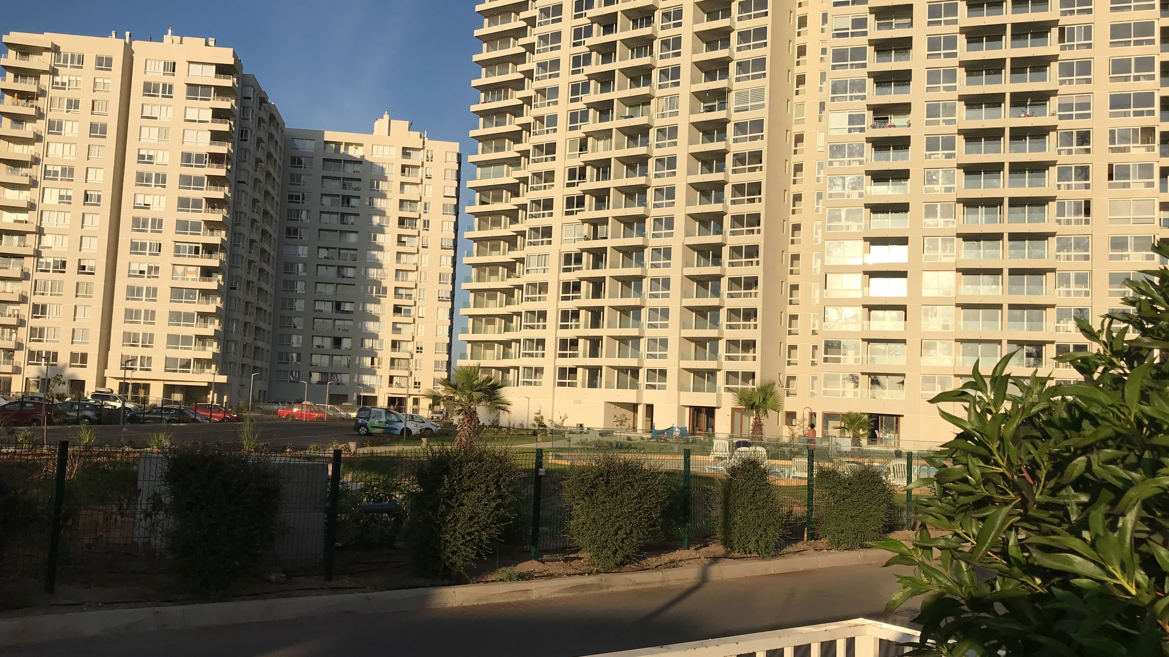 A high-rise residential building with multiple balconies and a clear sky.