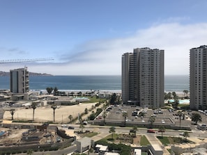 A coastal cityscape with high-rise buildings, a beach, and a parking area. - Portal Gran Marina Full Apartment (Coquimbo)