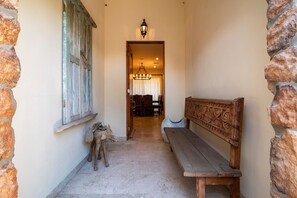 A narrow hallway with a wooden bench, a rustic stone wall, and a wooden door with shutters. - Paraiso Del Mar Resort V58 4 Bed by Casago (La Paz)