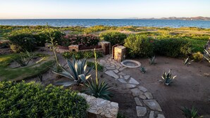 A landscaped garden with a stone pathway leading to a seating area, surrounded by various plants and shrubs. - Paraiso Del Mar Resort V58 4 Bed by Casago (La Paz)