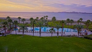 A resort with a swimming pool, palm trees, and a view of the ocean at sunset. - Paraiso Del Mar Resort V58 4 Bed by Casago (La Paz)