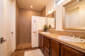 A bathroom with two sinks, a mirror, and a shower.