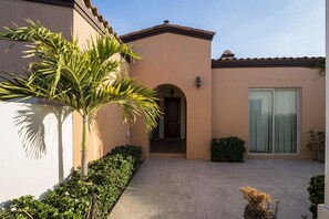 A building with a beige facade, a tiled roof, and a large glass door. - Paraiso Del Mar Resort V103 3 Bed by Casago (La Paz)