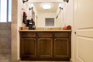 A bathroom with a granite countertop, a sink, a mirror, and a towel rack. - Paraiso Del Mar Resort B404 1 Bed by Casago (La Paz)