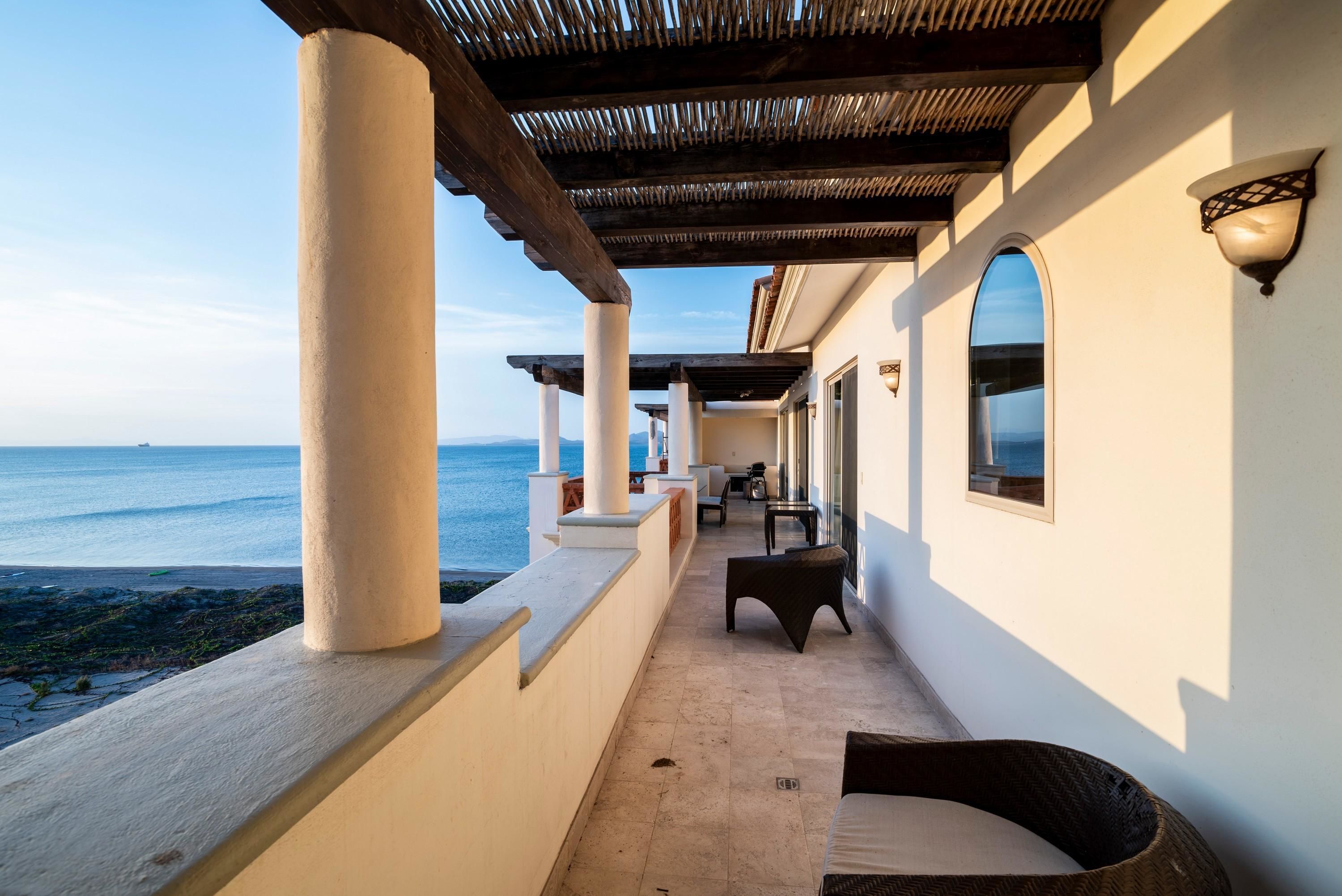 Un espacio al aire libre cubierto con vista al mar, que incluye un conjunto de asientos y una estructura de pérgola.