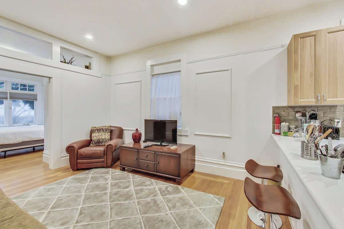 A living room with a sofa, TV, and a dining area with a kitchen counter.