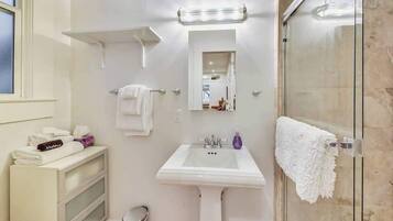 A bathroom with a white sink, a glass shower enclosure, a mirror, and a towel rack.
