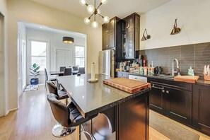A modern kitchen with dark cabinets, a central island, and a dining area with chairs.