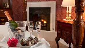 A table with a bottle of champagne, two glasses, and chocolate-covered strawberries on a white tablecloth. - Churchill Manor B&B (Napa)