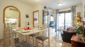 Un coin repas avec une table dressée pour quatre personnes, un canapé et un téléviseur en arrière-plan.