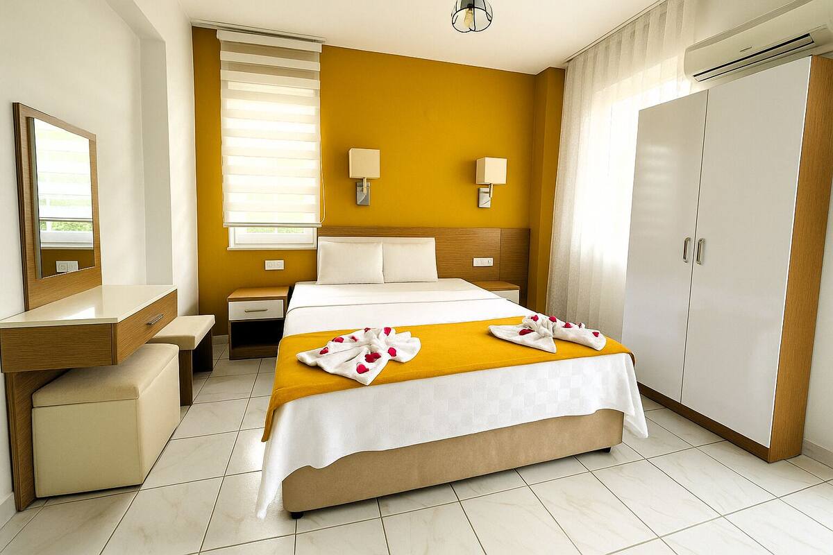 A hotel room with a bed, a desk, a wardrobe, and a bathroom mirror.