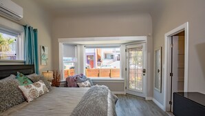 Ein Schlafzimmer mit einem großen Bett, einem Fernseher und Blick ins Freie.