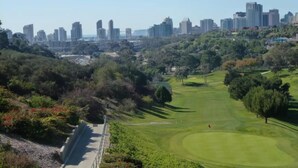 Ein Golfplatz mit Stadtansicht im Hintergrund.