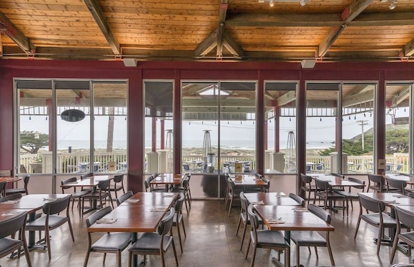 Un restaurant avec de grandes fenêtres, des tables et des chaises en bois.